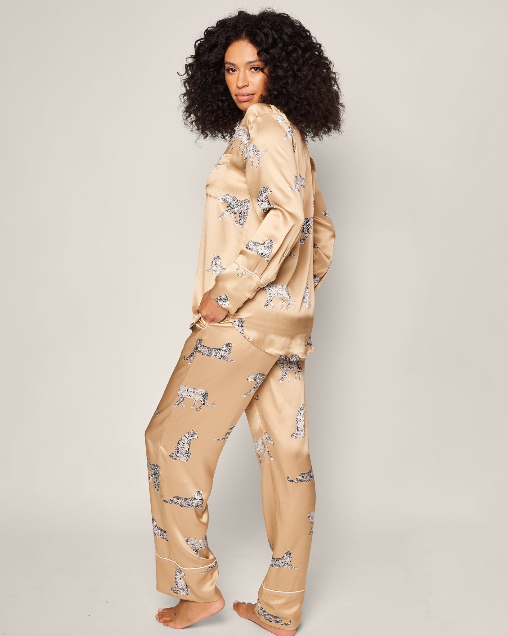 Woman wearing beige pajamas with a pattern on a plain background