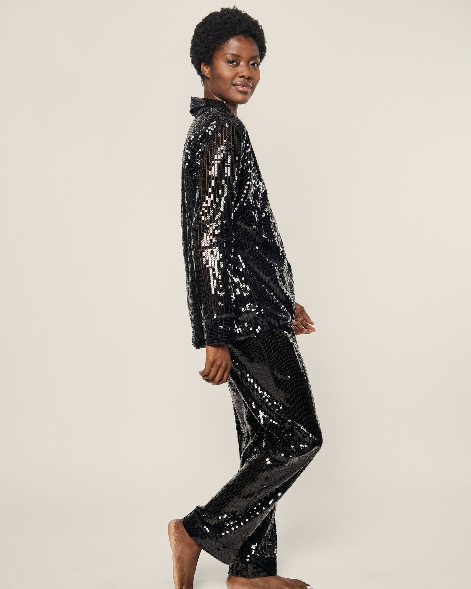 Person wearing a black sequin outfit on a plain background