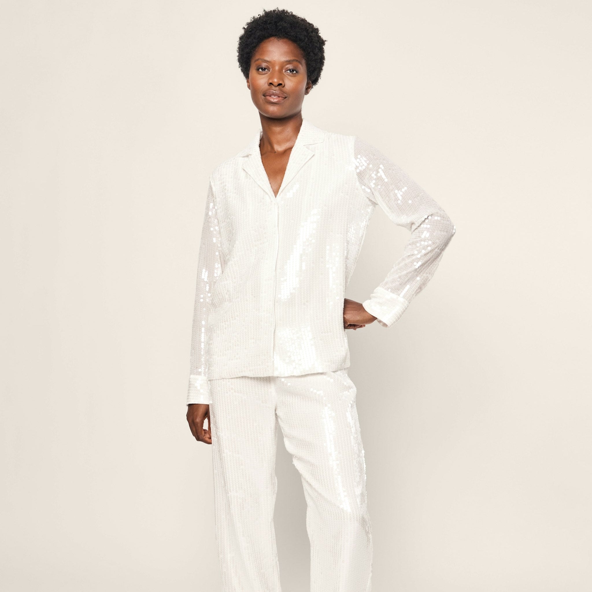 Person wearing a white satin pajama set on a plain background