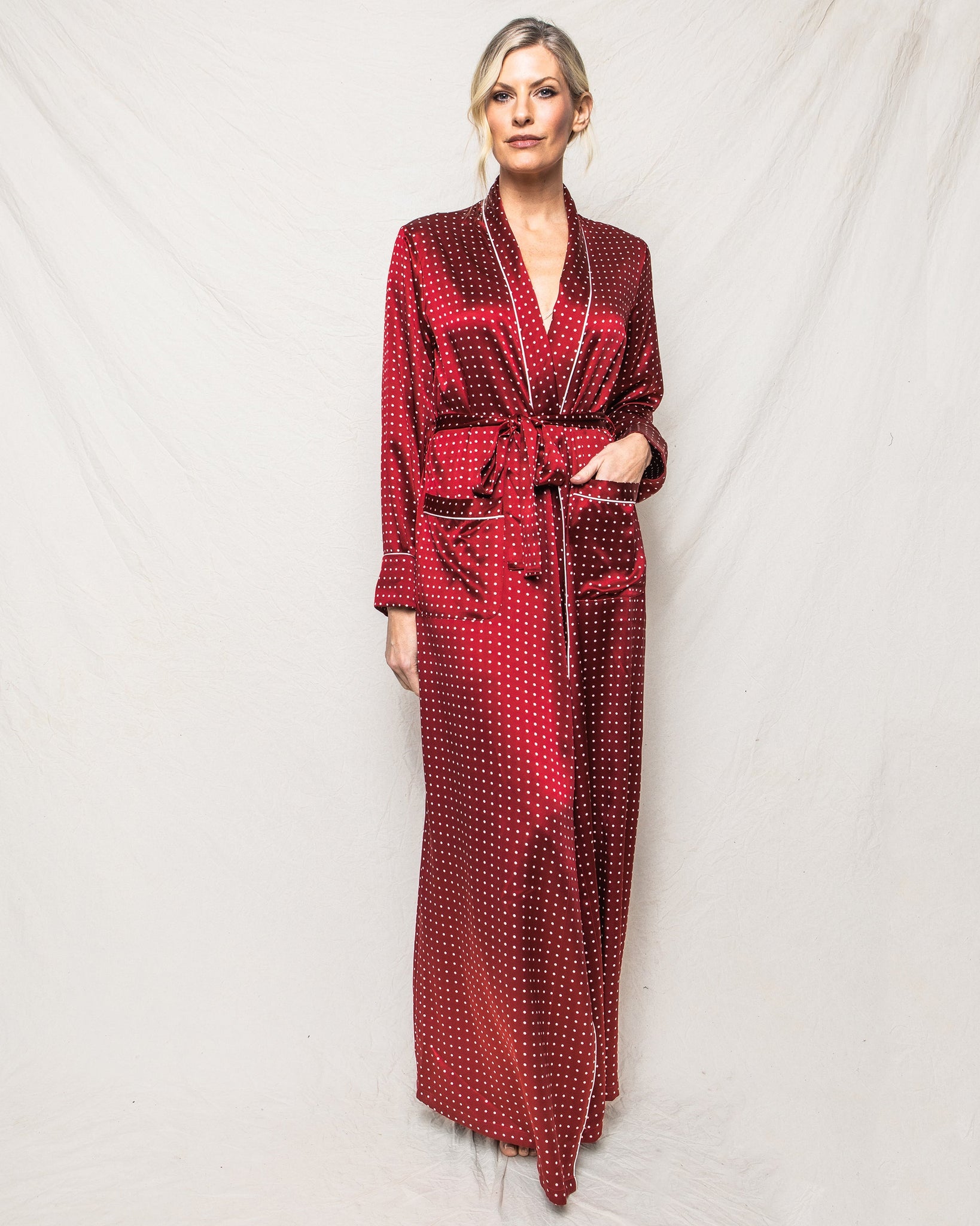 Woman wearing a red patterned robe against a white background 