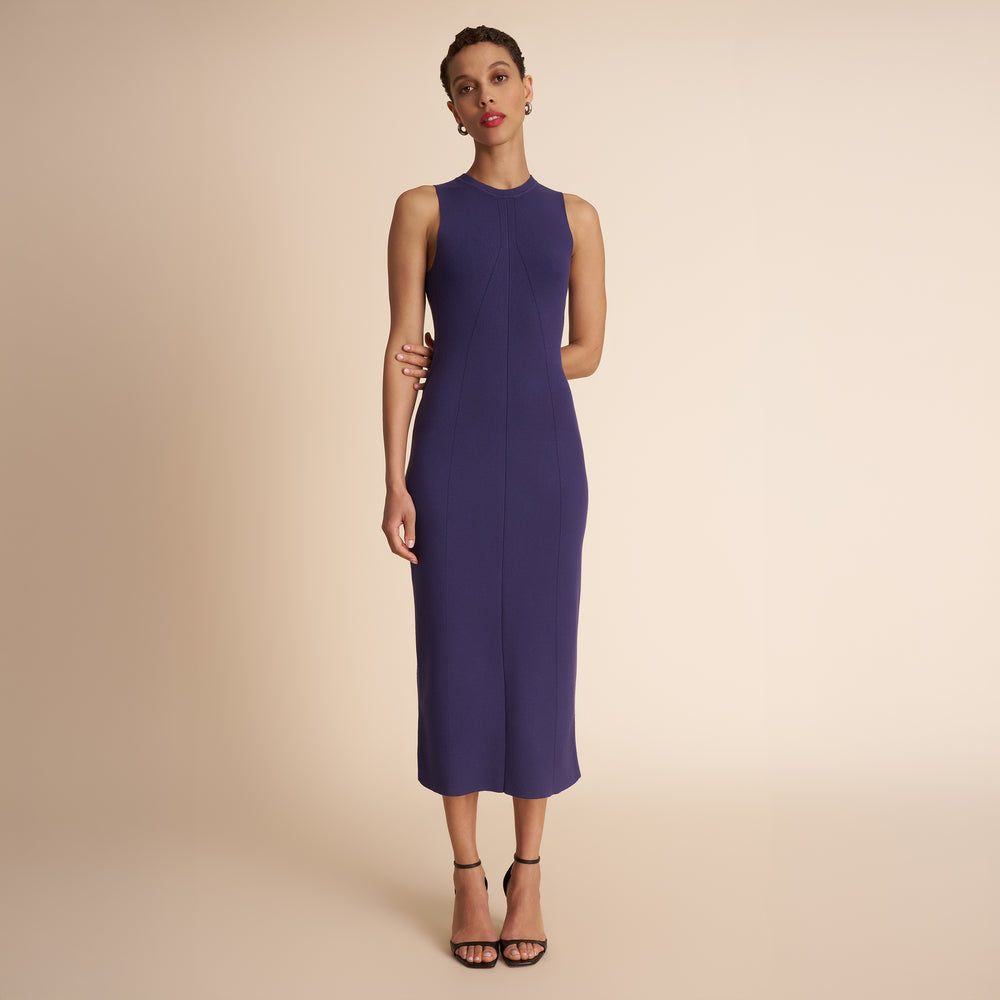 Woman wearing a sleeveless purple dress against a beige background
