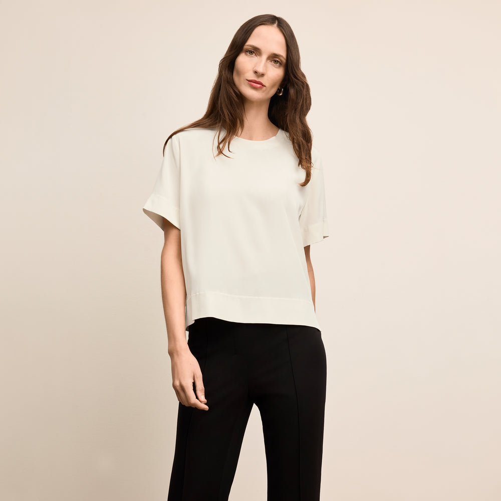 Woman wearing a white blouse and black pants on a beige background