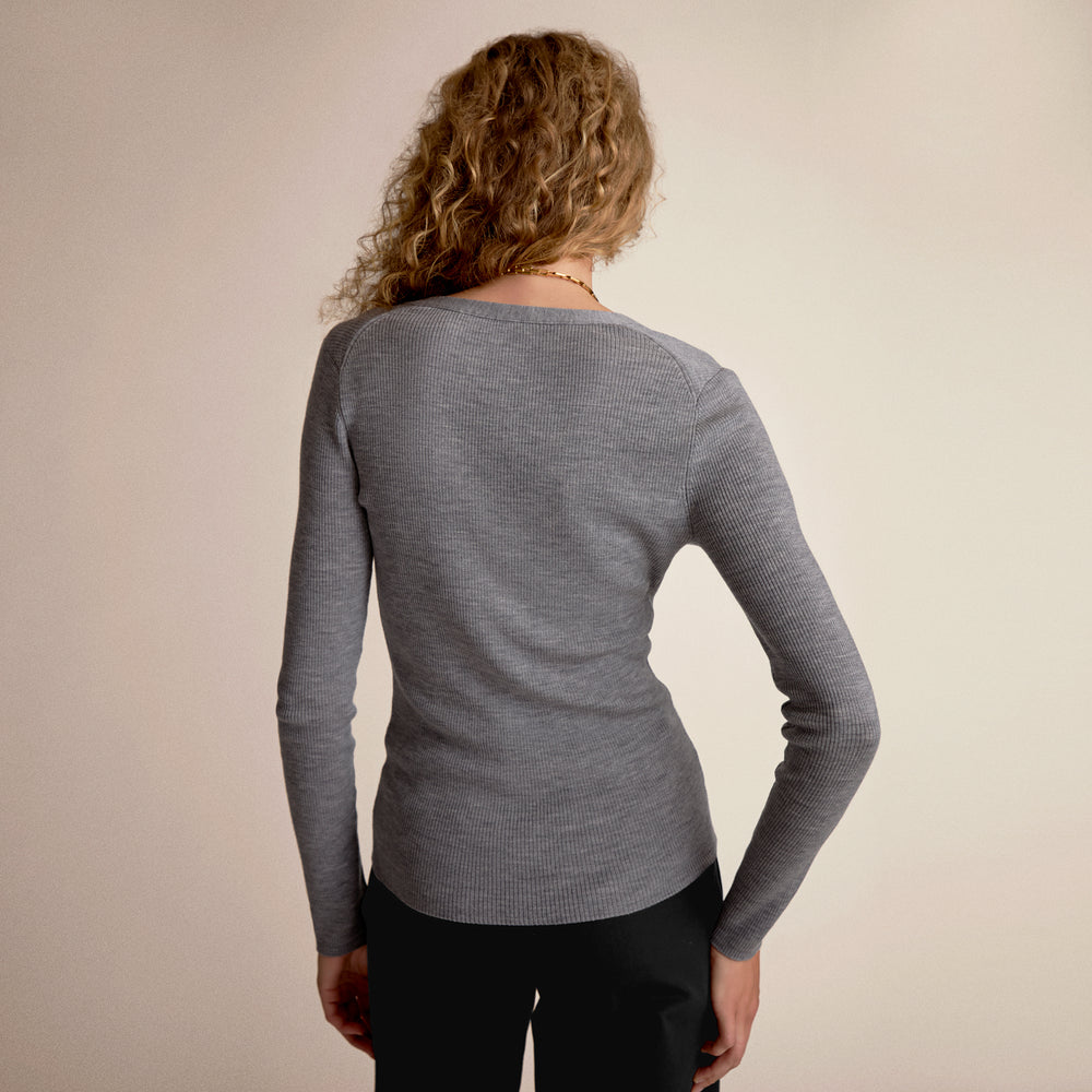 Person wearing a gray long-sleeve shirt against a beige background