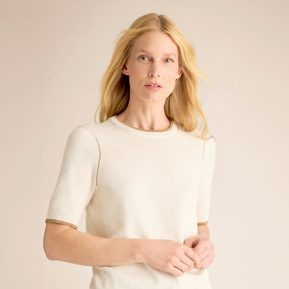 Woman wearing a white blouse against a beige background