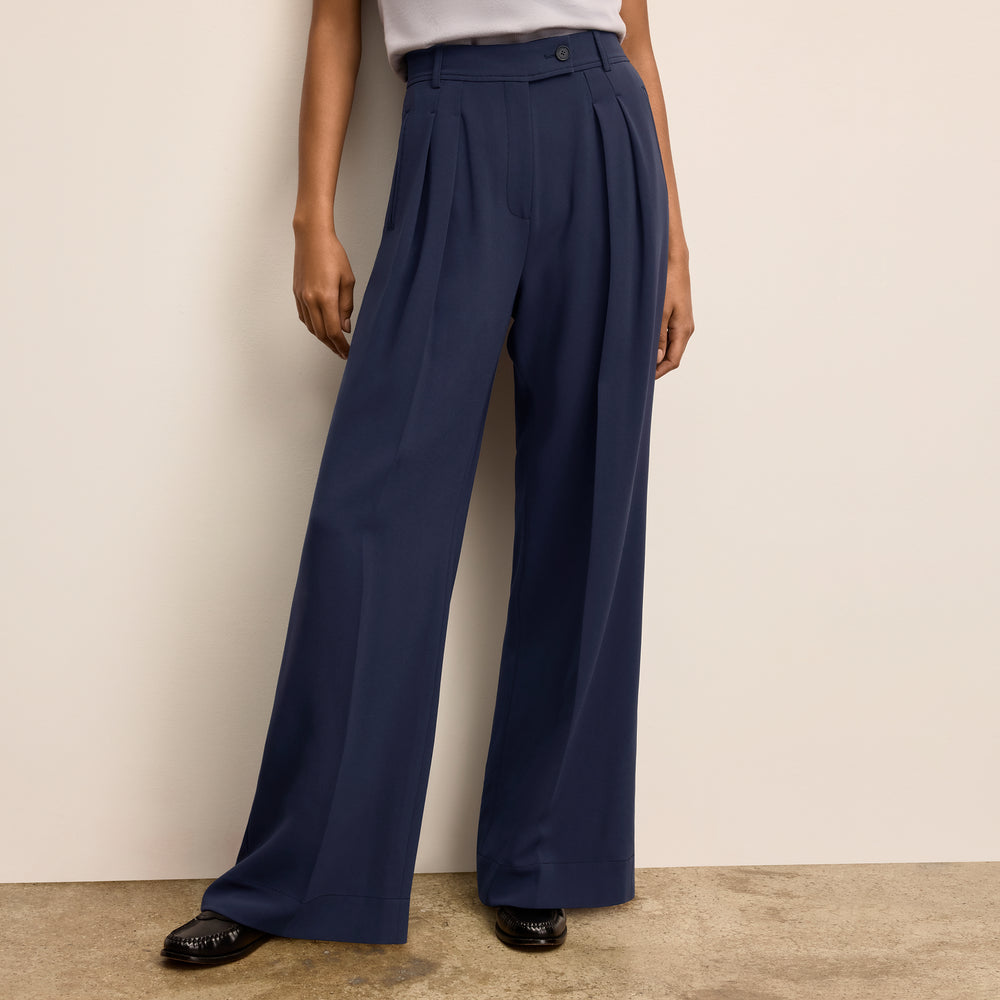 Navy wide-leg pants worn by a woman against a beige wall