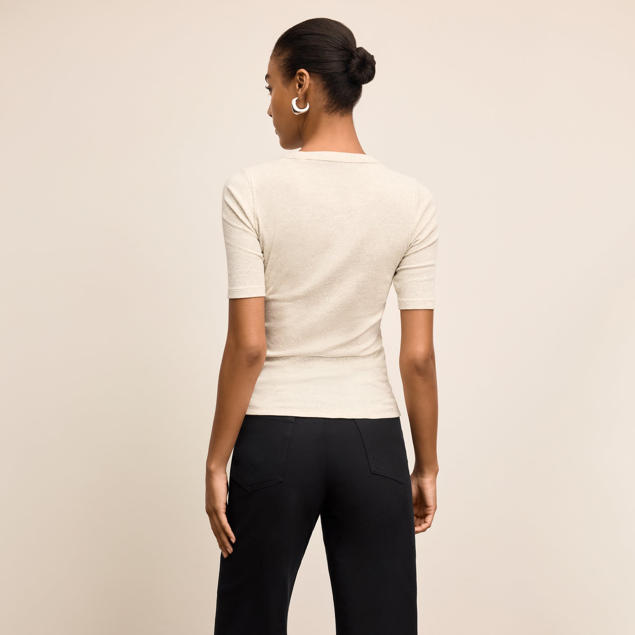 Person wearing a beige top and black pants on a beige background