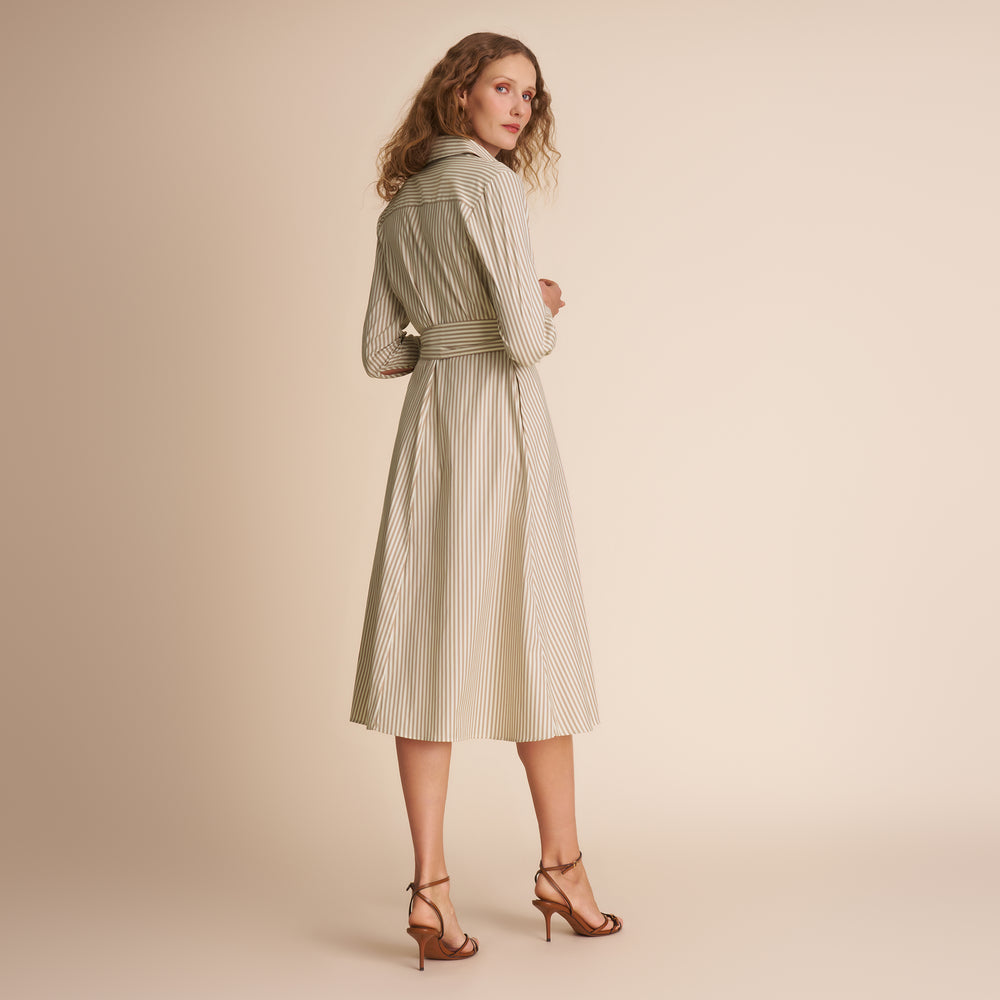 Woman wearing a green and white striped dress on a beige background
