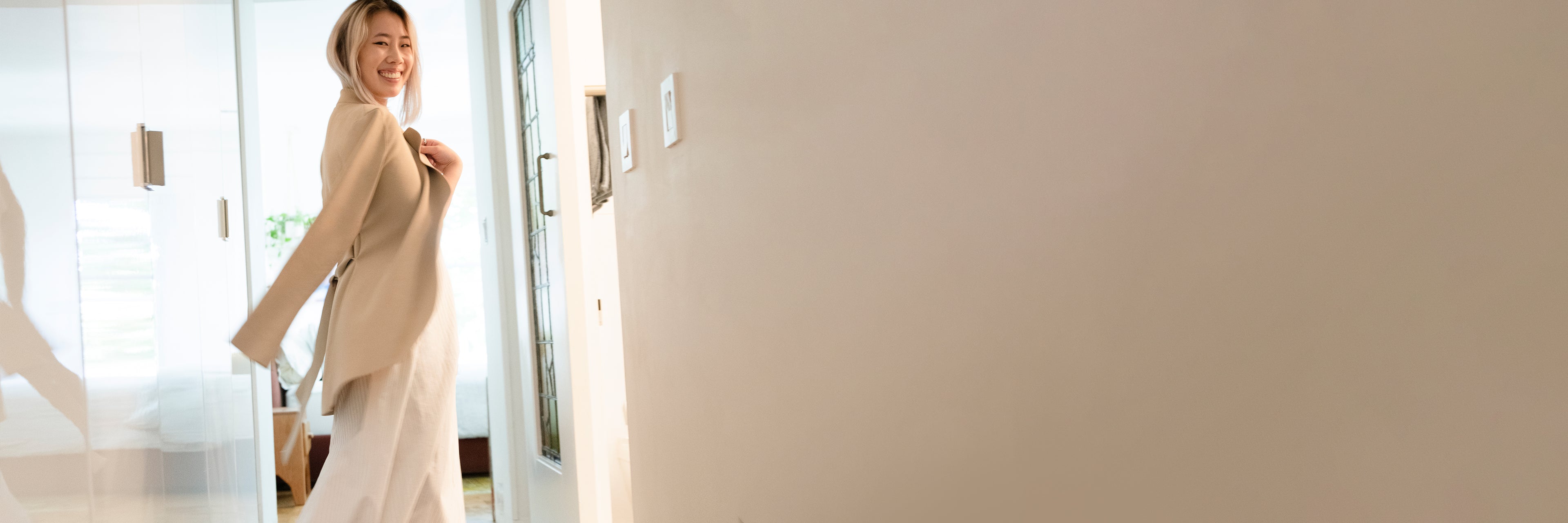 Woman in a beige coat standing in a modern interior setting