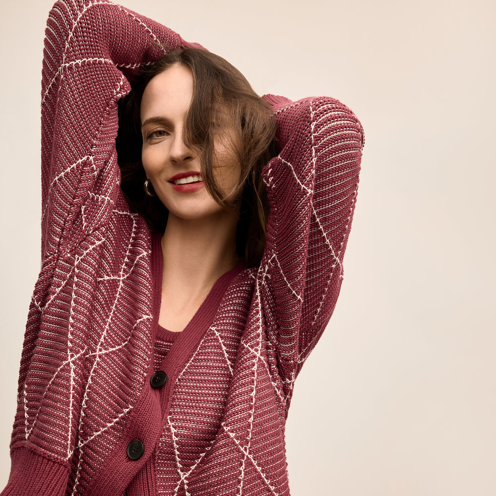 Woman wearing a maroon knitted cardigan against a beige background