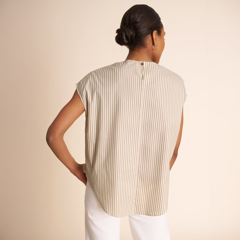 Woman wearing a sleeveless striped shirt against a beige background