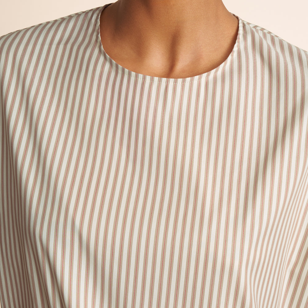 Close-up of a person wearing a beige and white striped shirt.