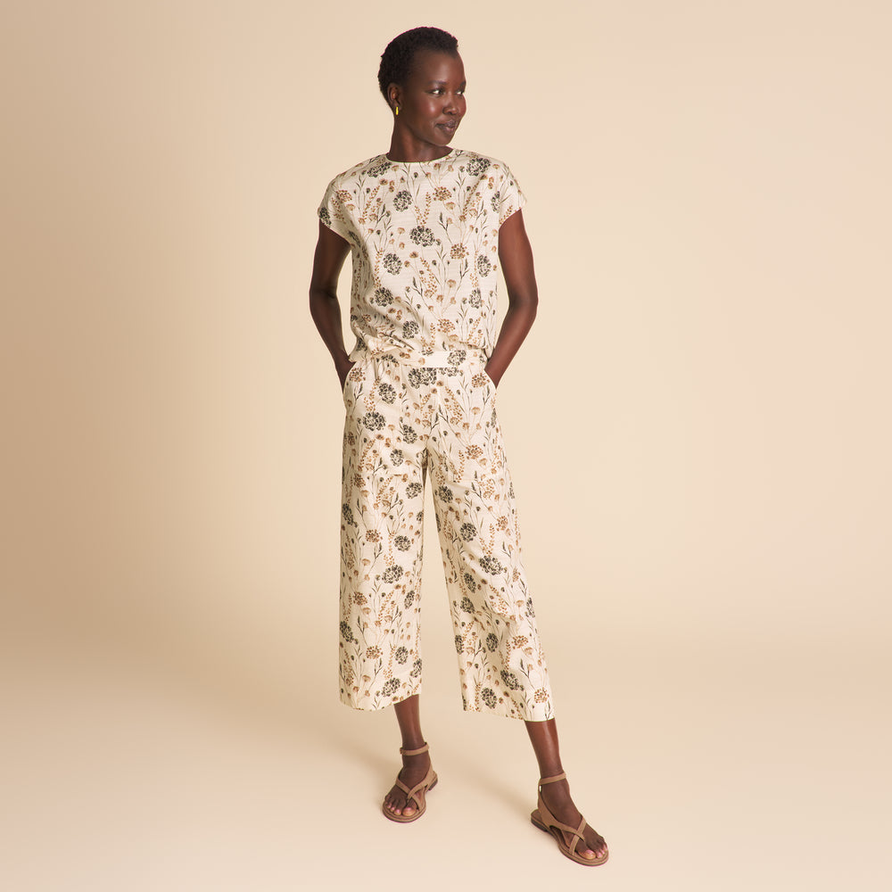 Woman wearing a floral jumpsuit on a beige background