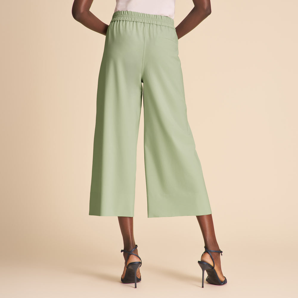 Person wearing light green wide-leg pants on a beige background
