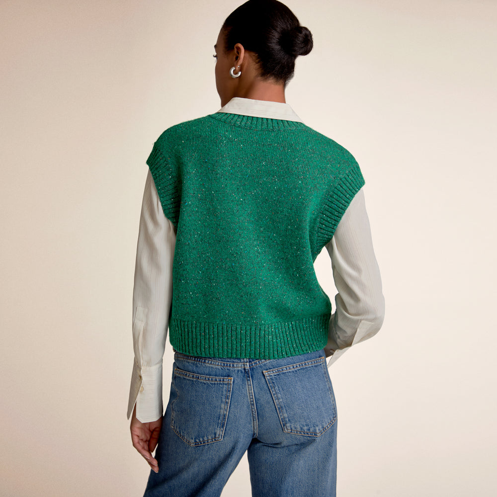 A womans back wearing a green sweater vest