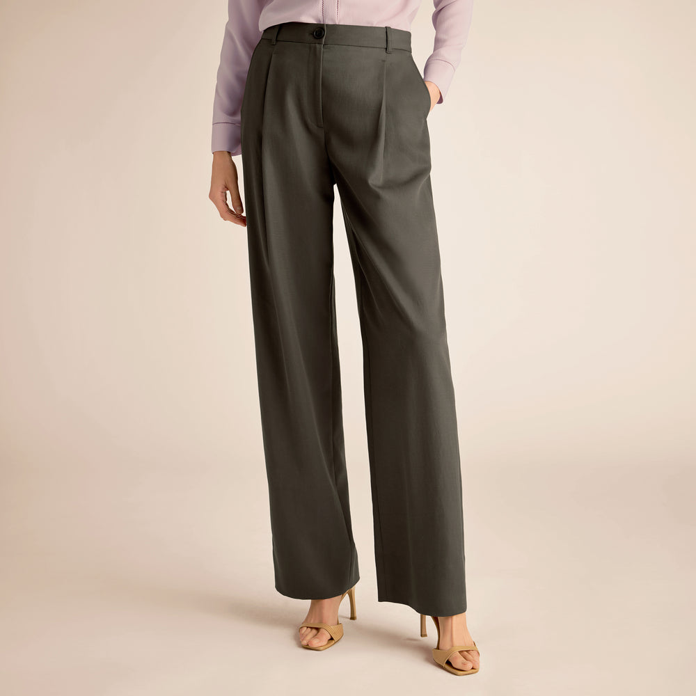 Person wearing dark green wide-leg pants on a beige background
