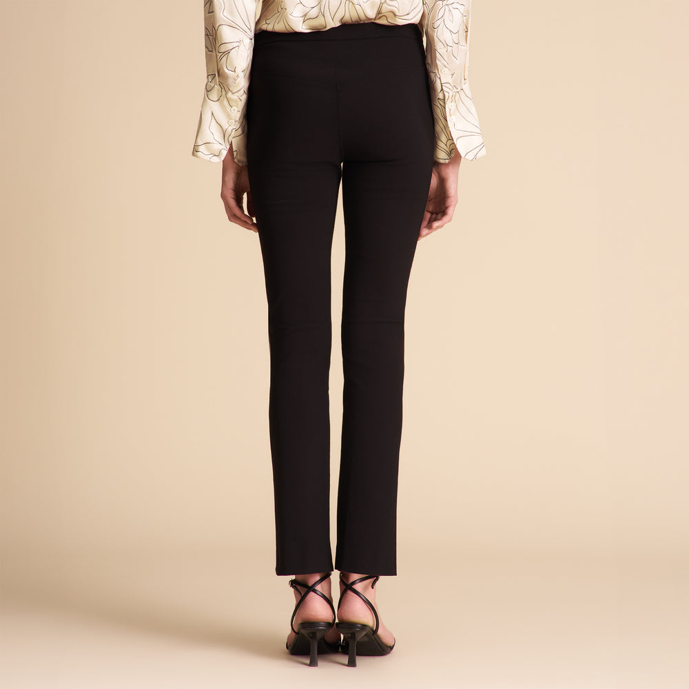 Person wearing black pants and a patterned top on a beige background