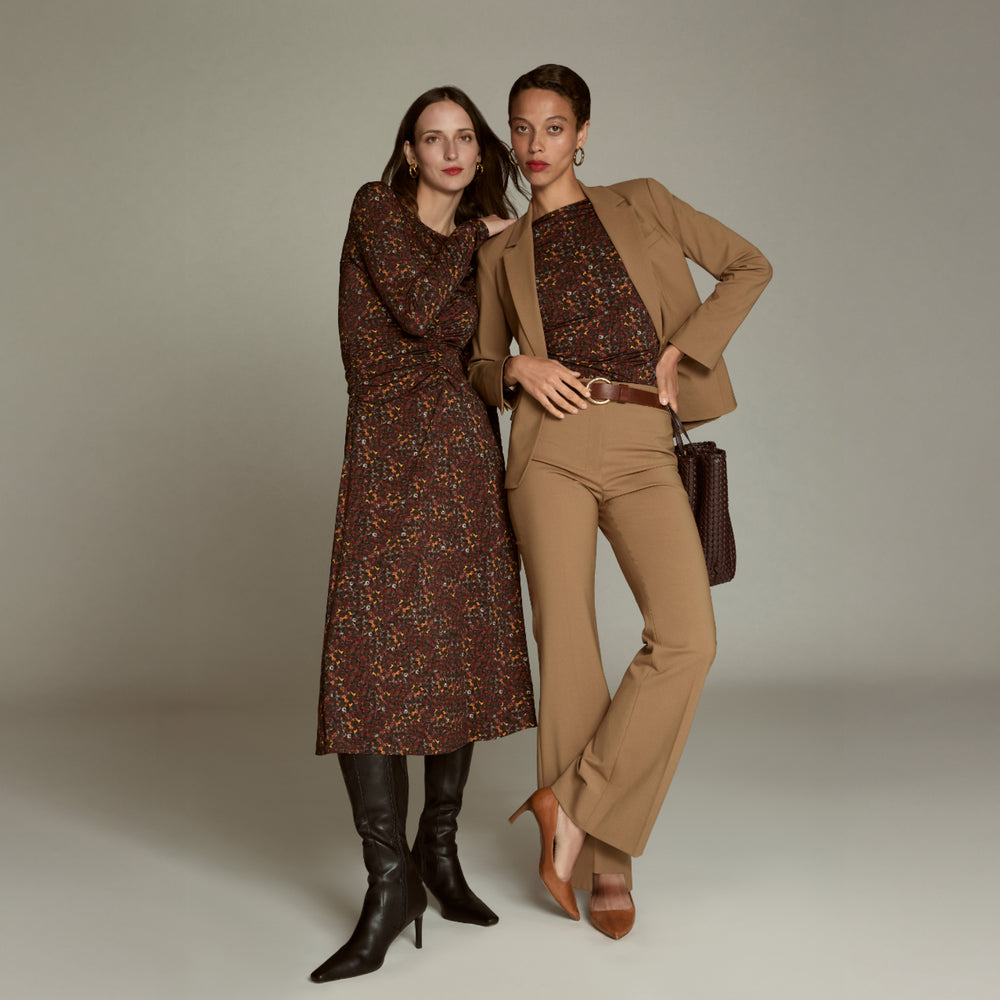 Two women in vintage-style clothing posing against a plain background
