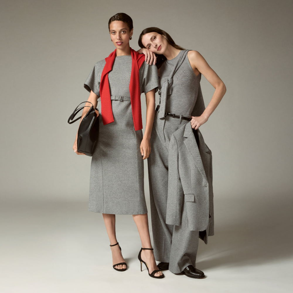 Two women wearing gray outfits with red and black accents against a neutral background