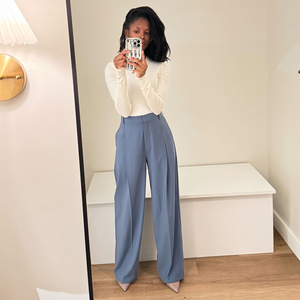 Person wearing a white sweater and blue pants taking a mirror selfie.