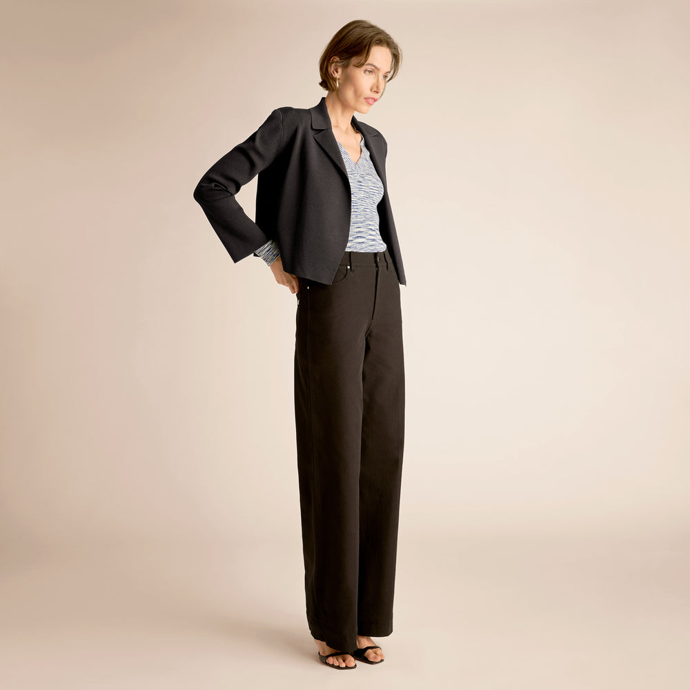 Woman wearing a black suit on a beige background