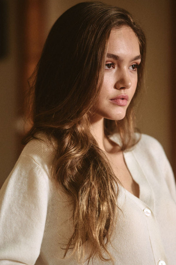 Woman with long hair wearing a white shirt in a warm-toned room