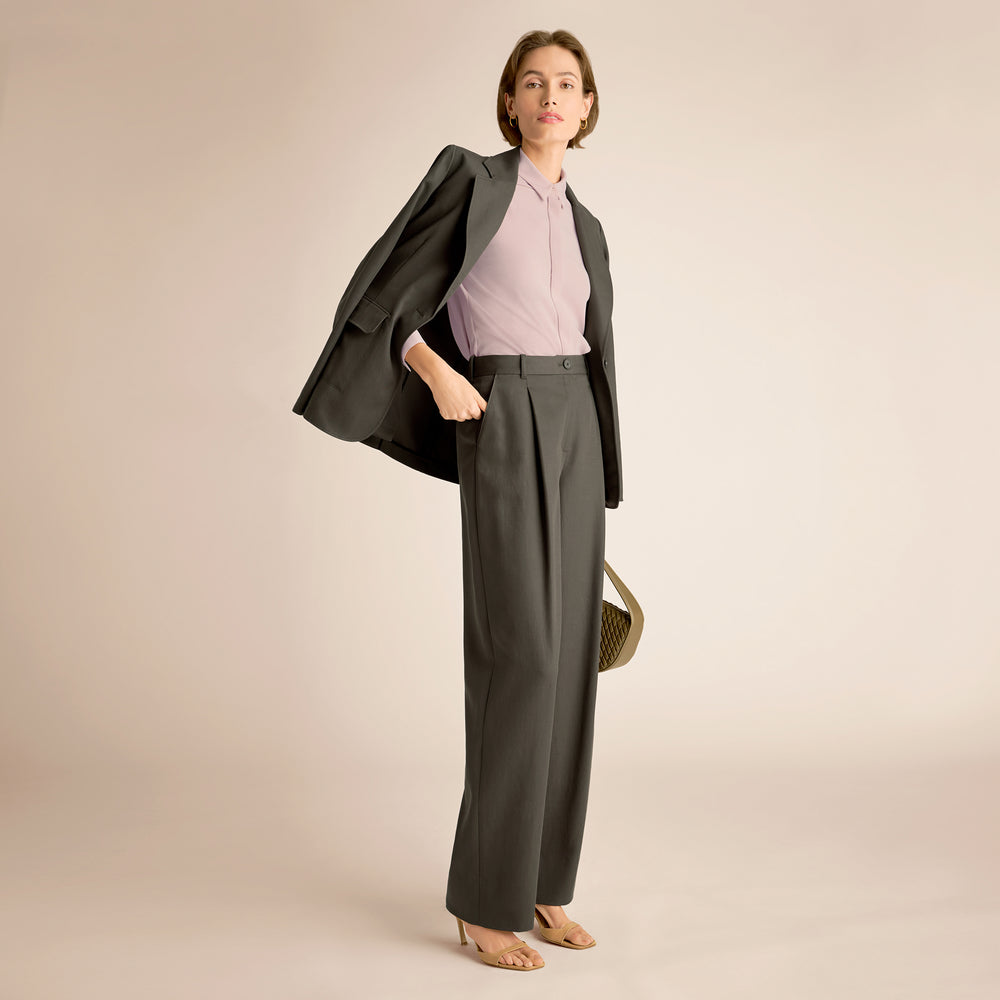 Woman wearing a gray suit with a pink top on a beige background