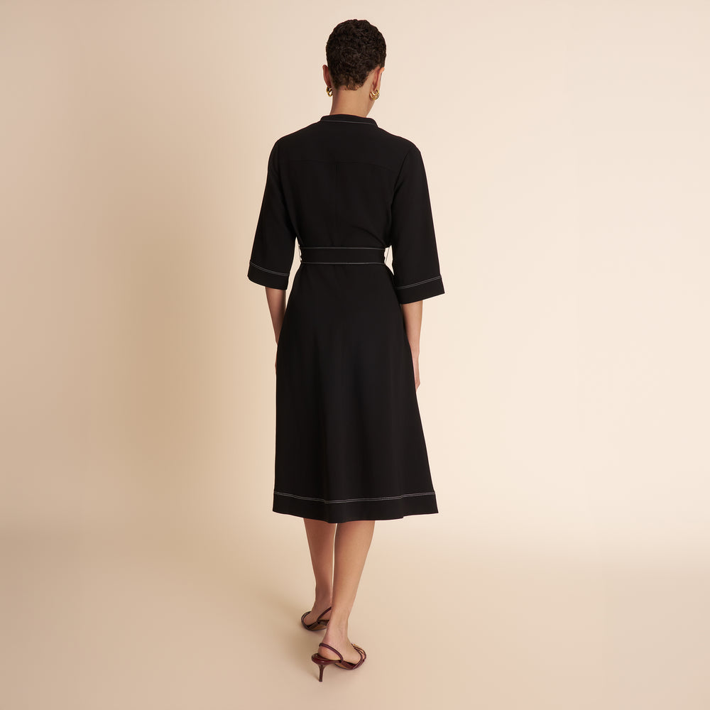 Woman wearing a black dress with a belt on a beige background