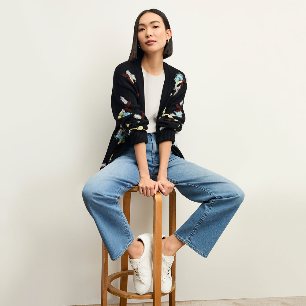 front image of a woman sitting wearing the frame le jane ankle jeans in deepwater