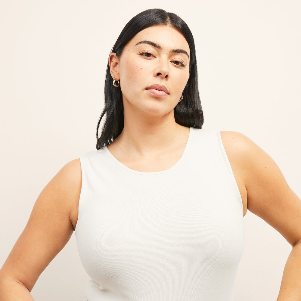 Front image of a woman standing sitting the paige top in fine ribbed cotton in ivory