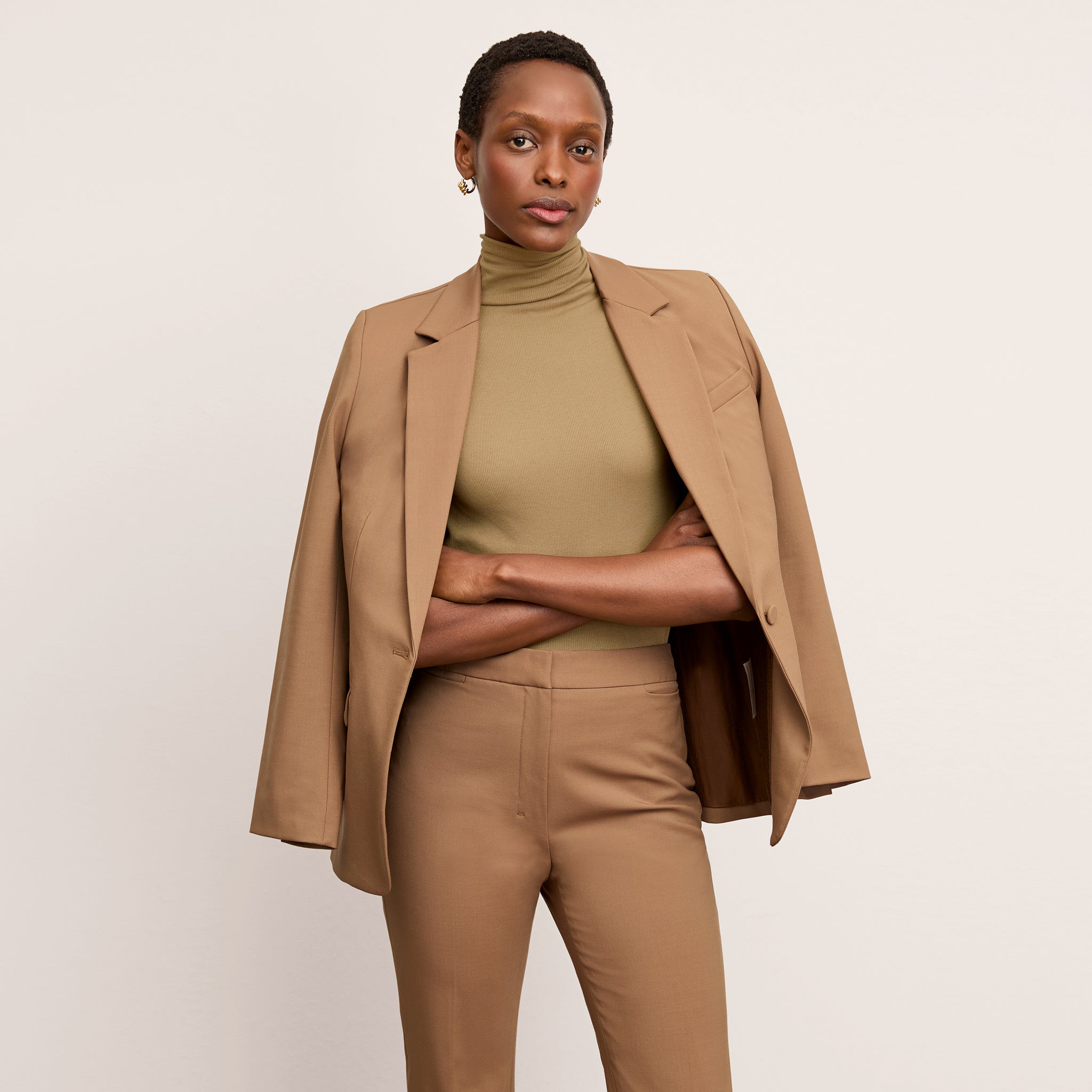 Front image of a woman standing wearing the Yiyan Blazer in Camel 