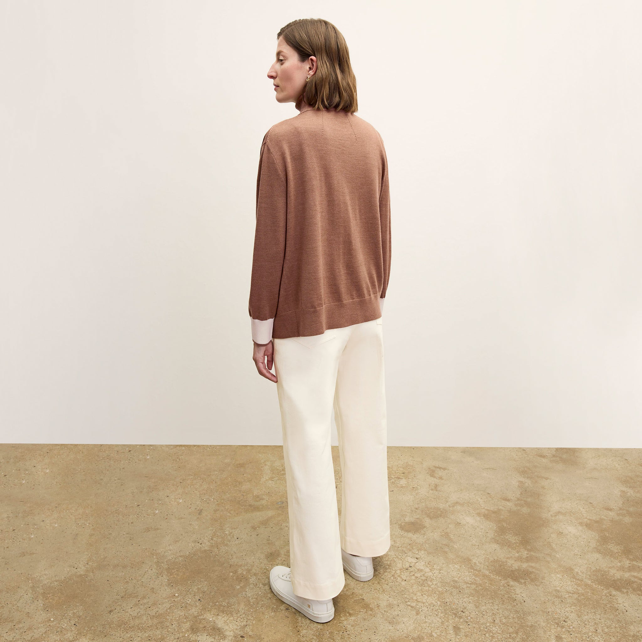 back image of a woman wearing the cookie cardigan in camel/ivory