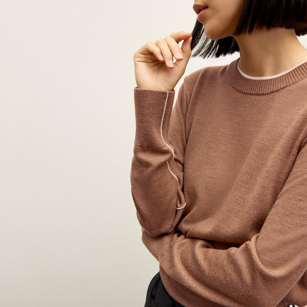 front image of a woman wearing the kit sweater in camel/ivory
