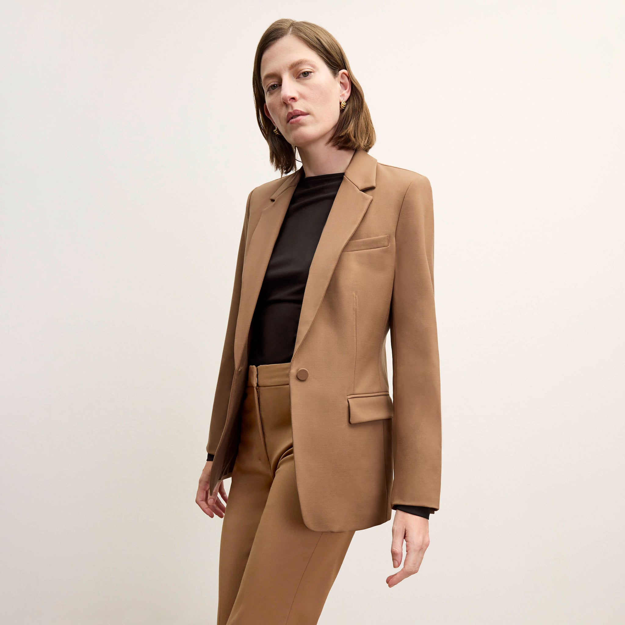 Front image of a woman standing wearing the Yiyan Blazer in Camel 