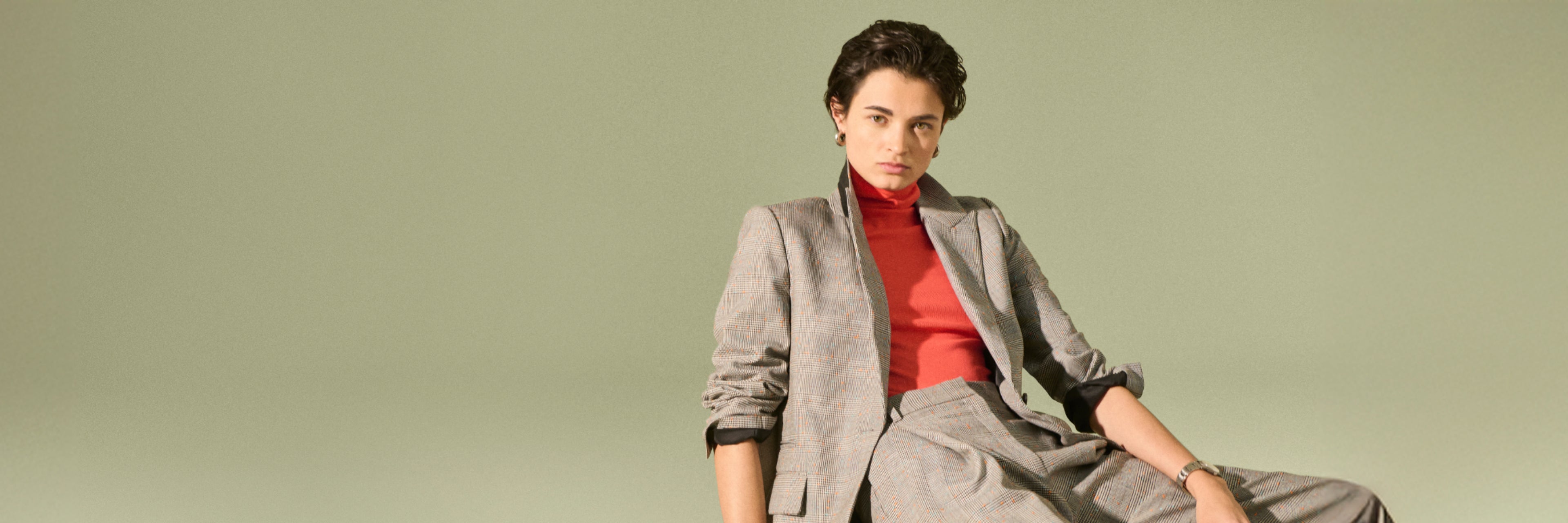 Image of a woman sitting wearing the tyner jacket and rina pant in mixed sharkskin