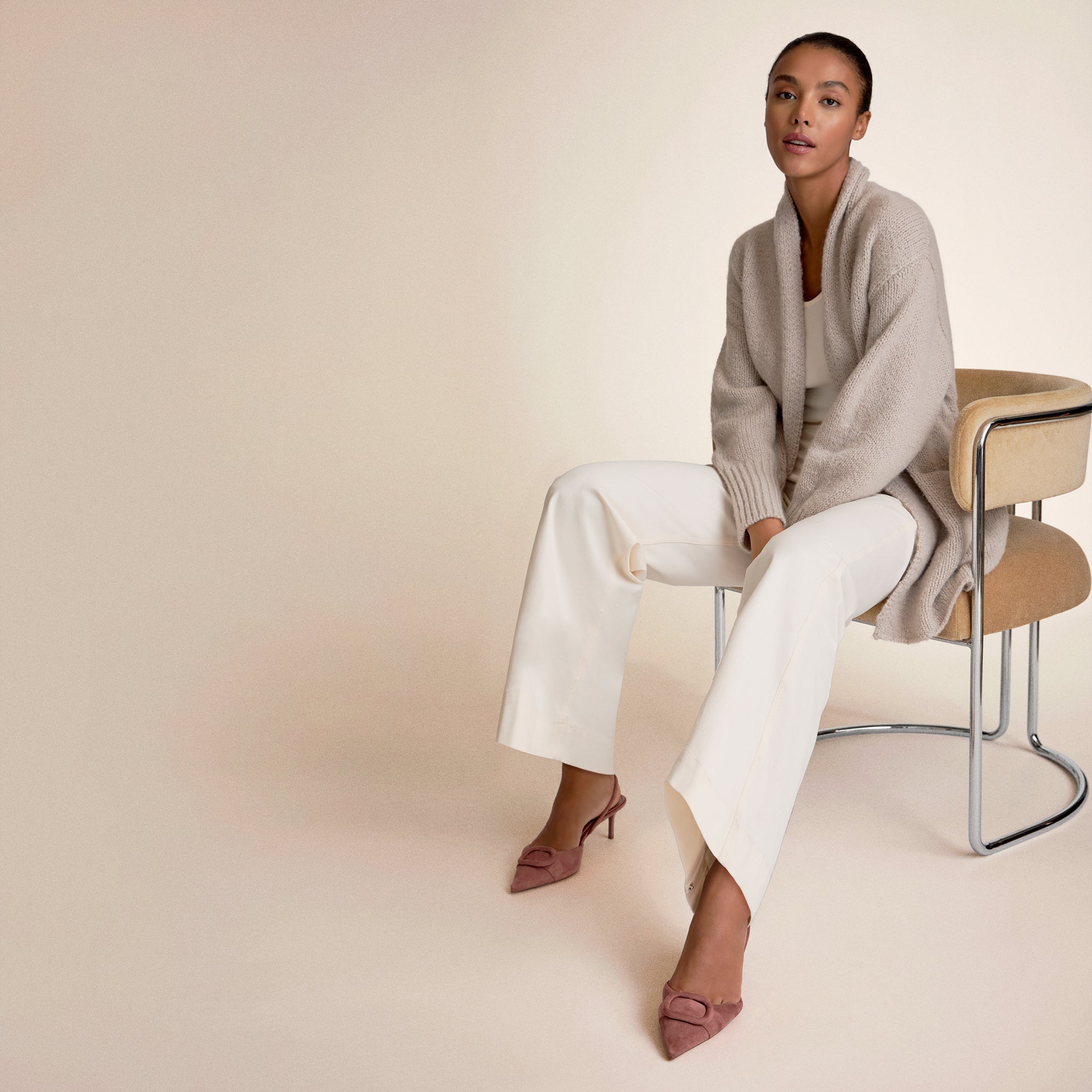 Woman wearing a light beige cardigan and white pants 