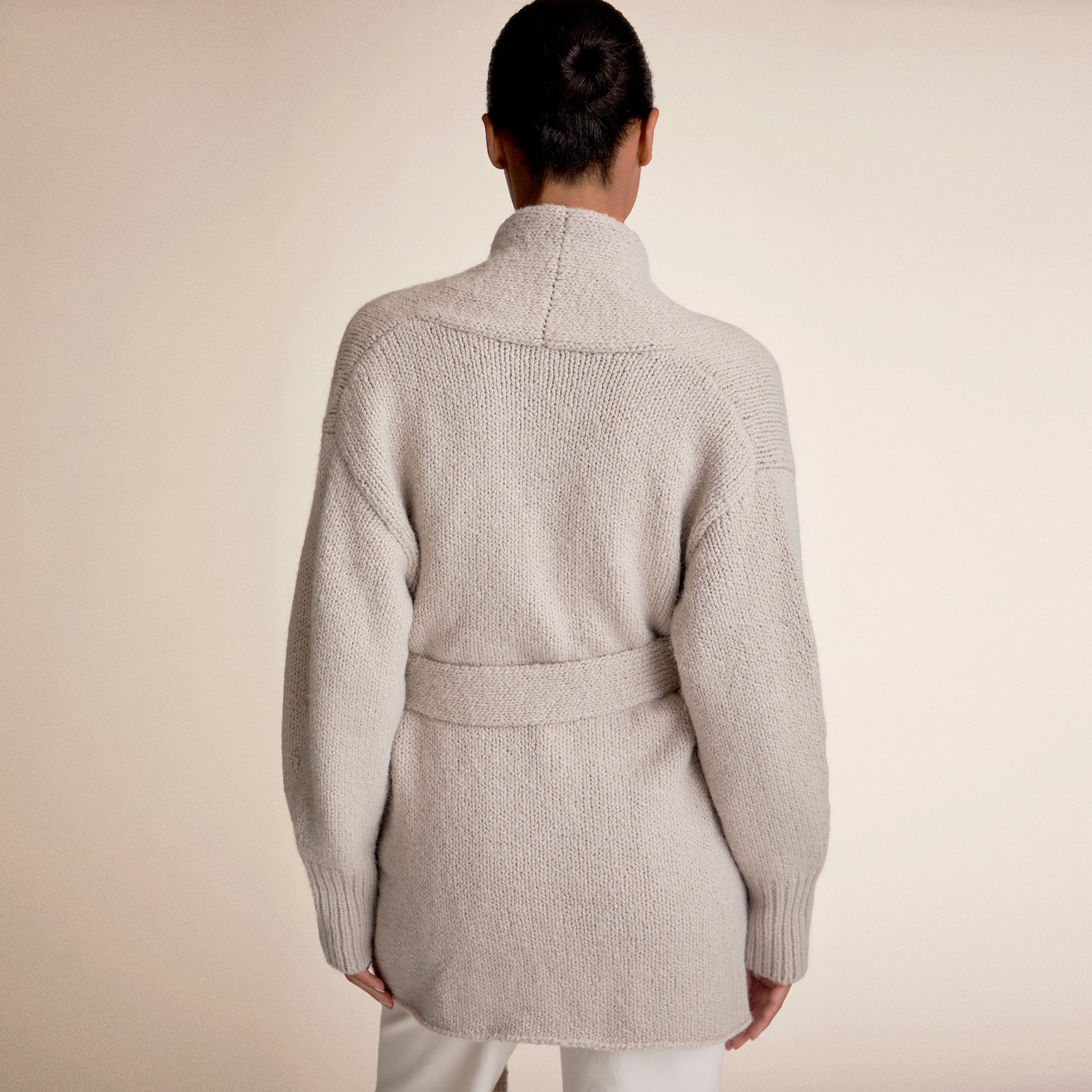 Woman wearing a light beige cardigan and white pants