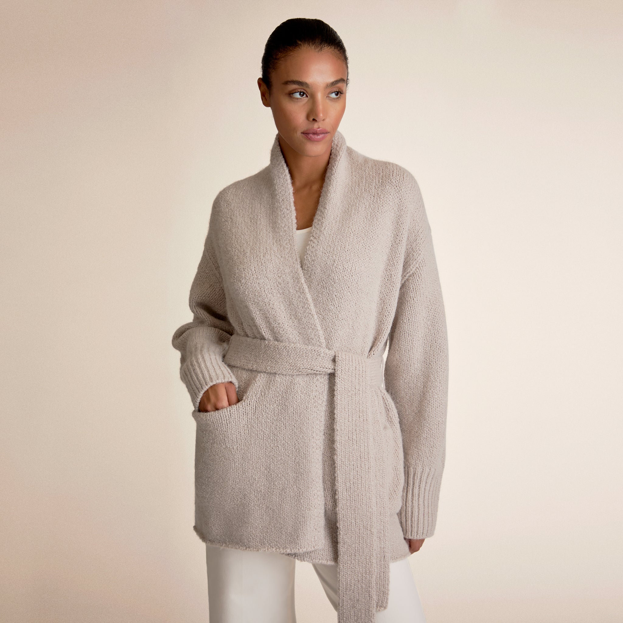 Woman wearing a light beige cardigan and white pants 