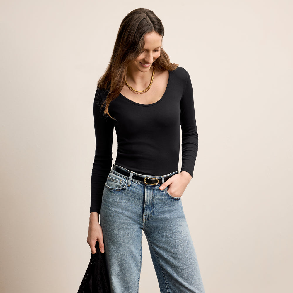 Front image of a woman standing wearing the marcia top in fine ribbed cotton in black