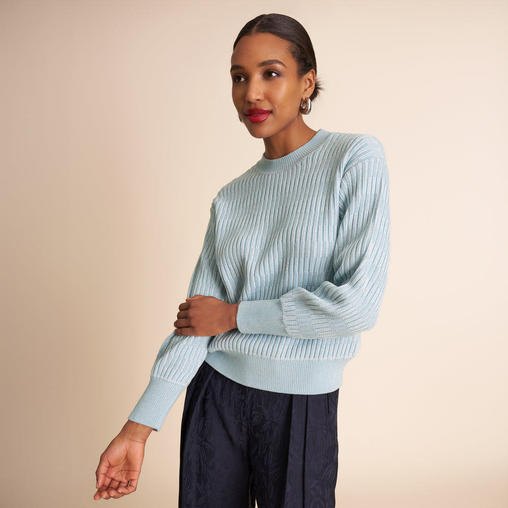 Woman wearing a light blue sweater against a beige background
