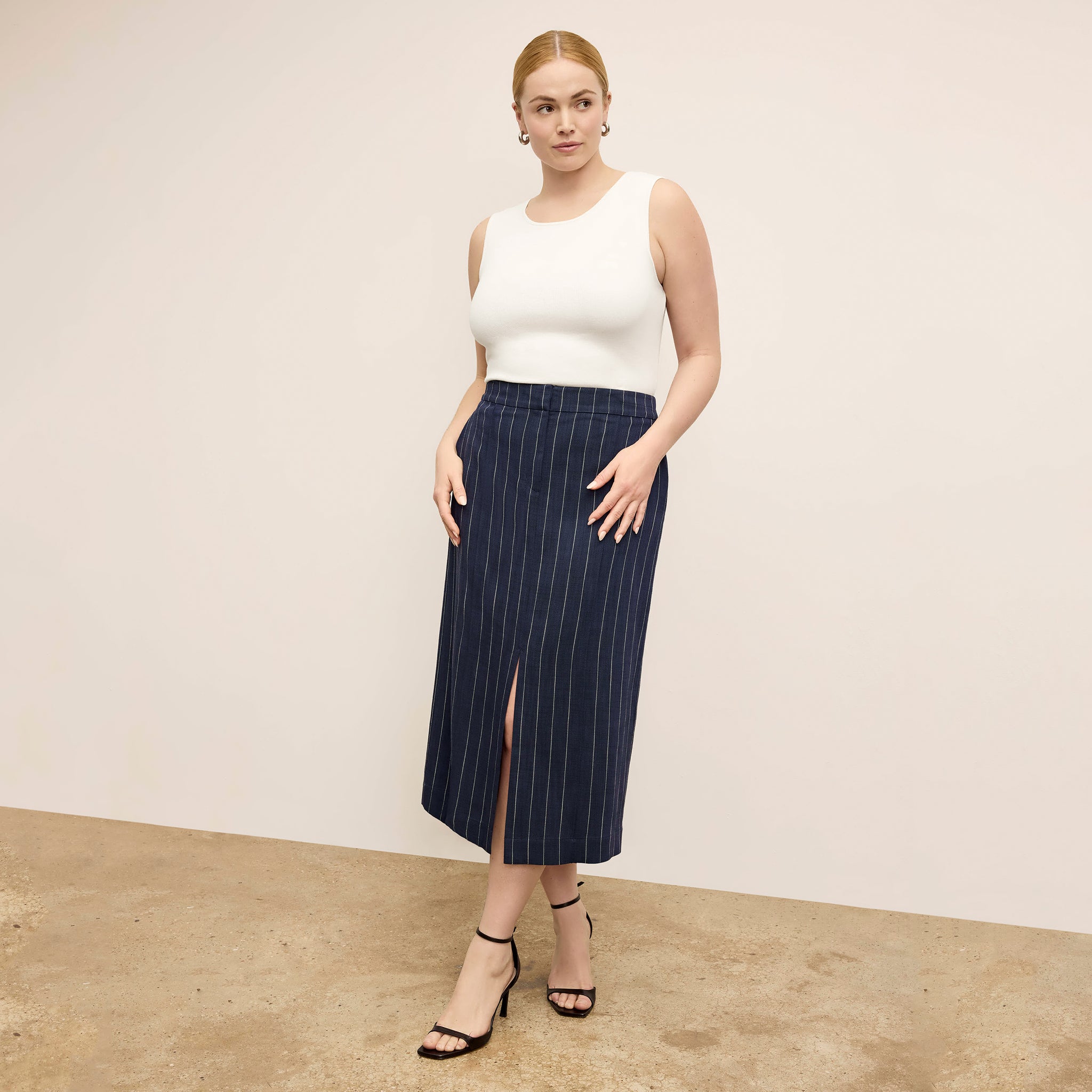 Front image of a woman standing wearing the paige top in fine ribbed cotton in ivory