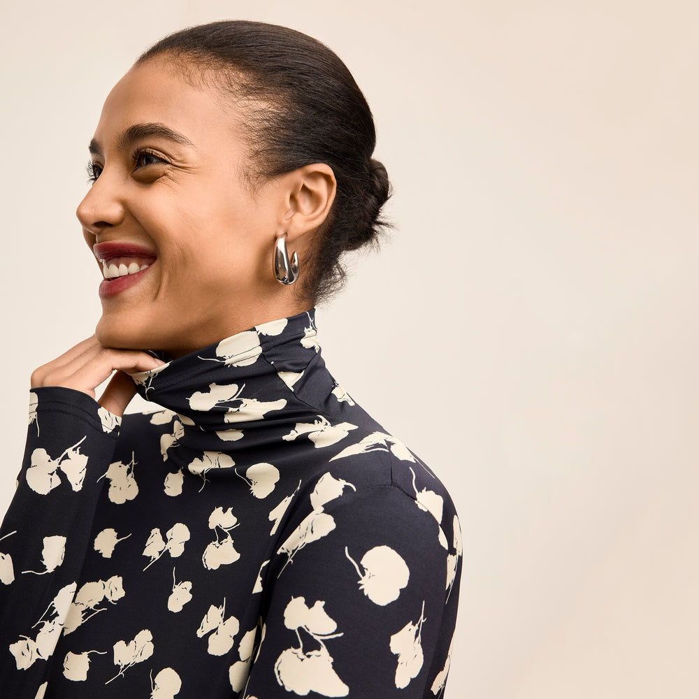 Woman wearing a navy blue sweater with white floral patterns on a beige background