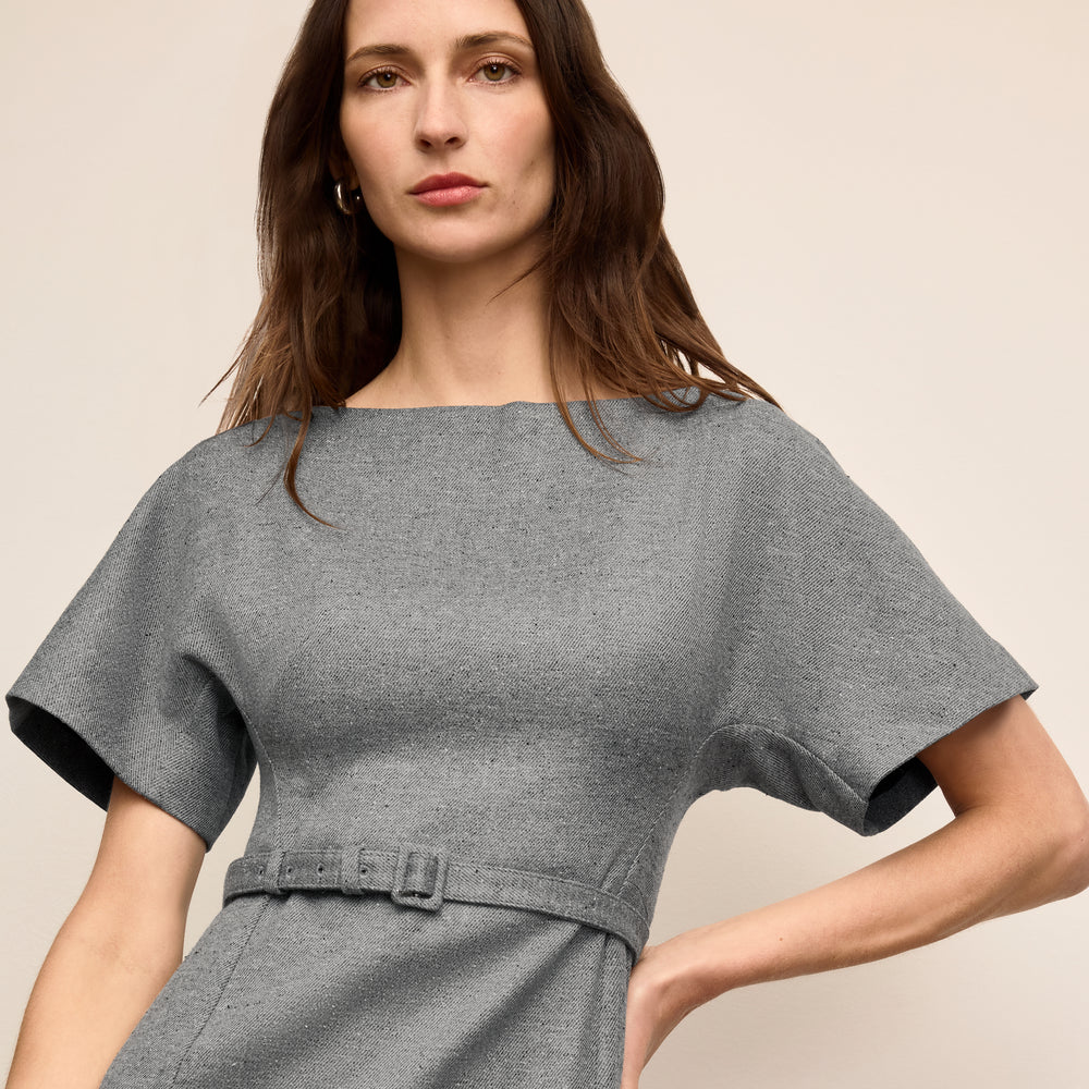 Woman wearing a gray dress against a beige background