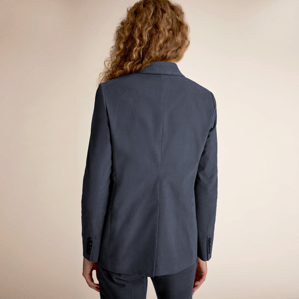 Person wearing a blue suit jacket on a beige background