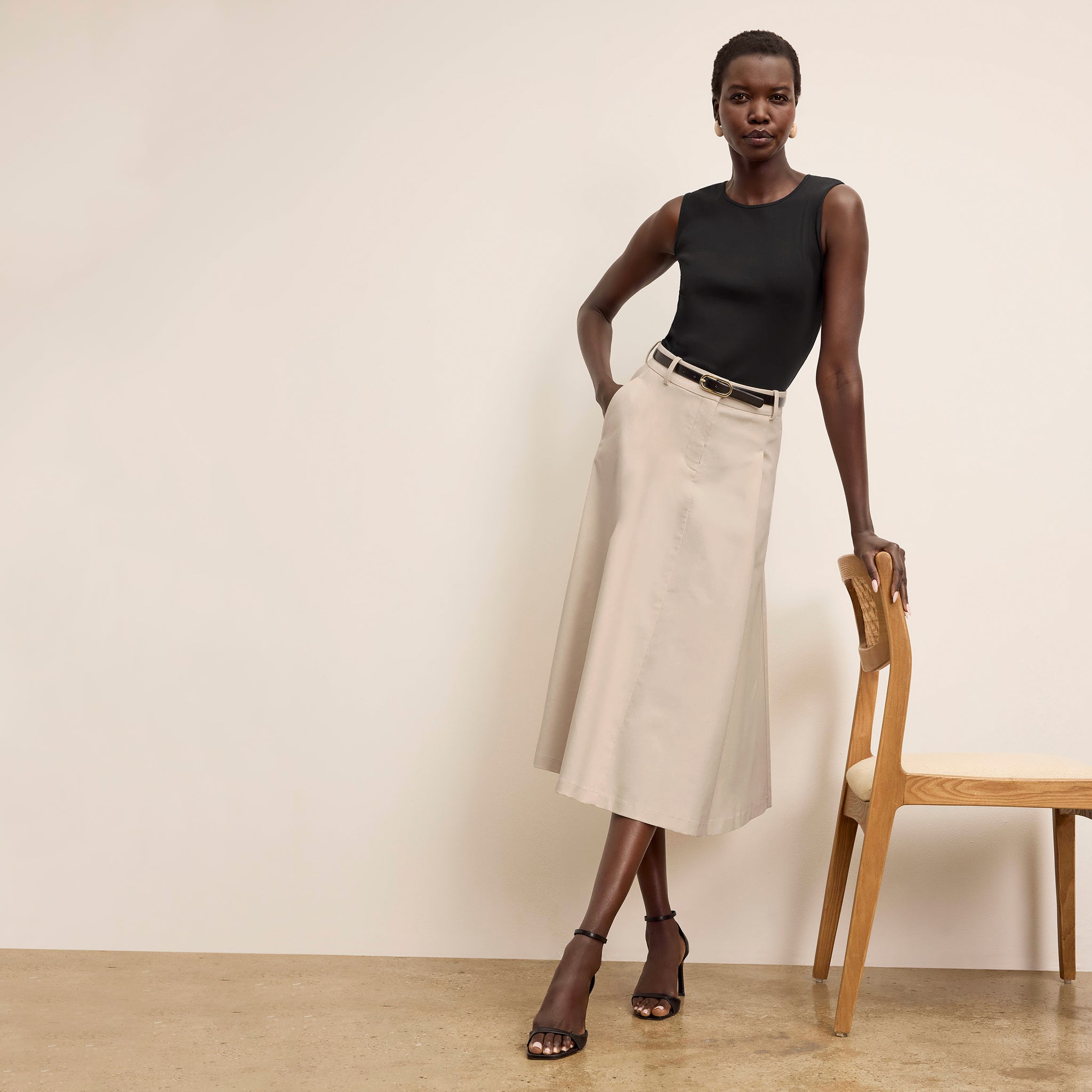 Front image of a woman standing wearing the paige top in fine ribbed cotton in black 