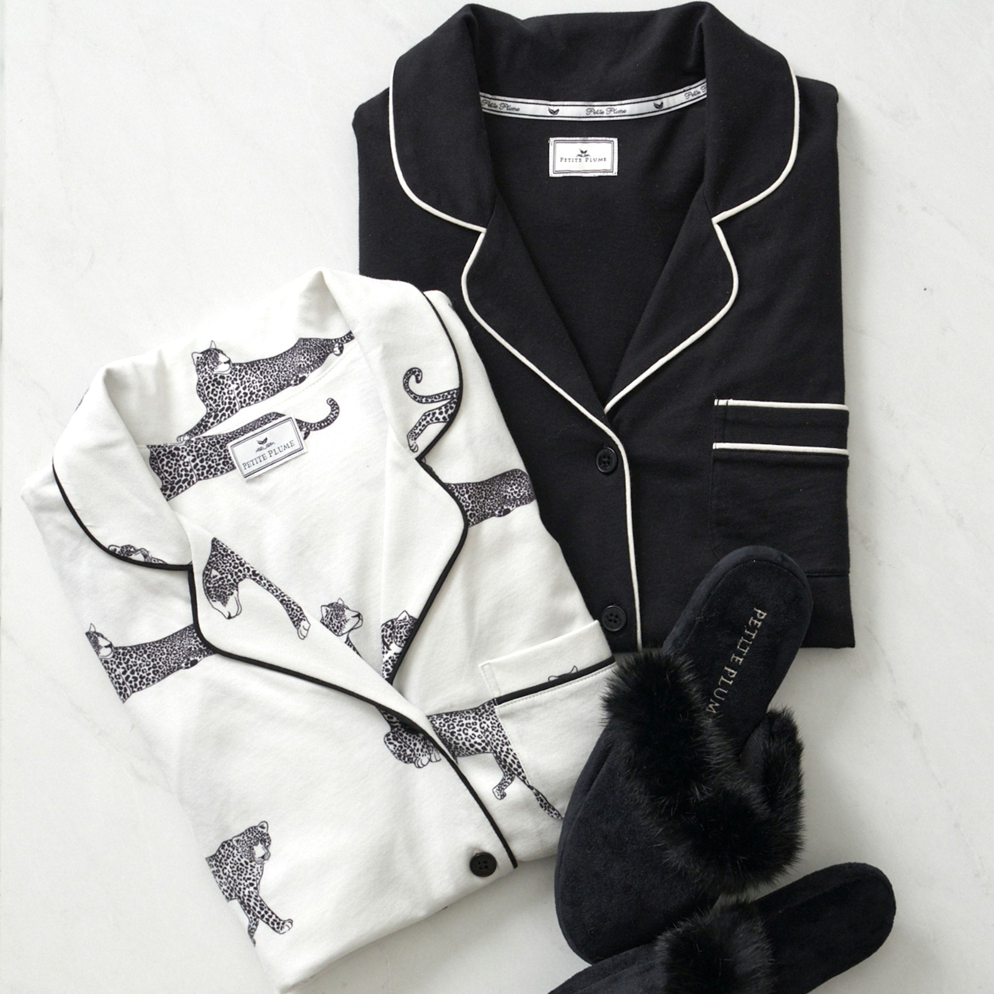 Black and white pajama set with embroidered designs and black slippers on a light background
