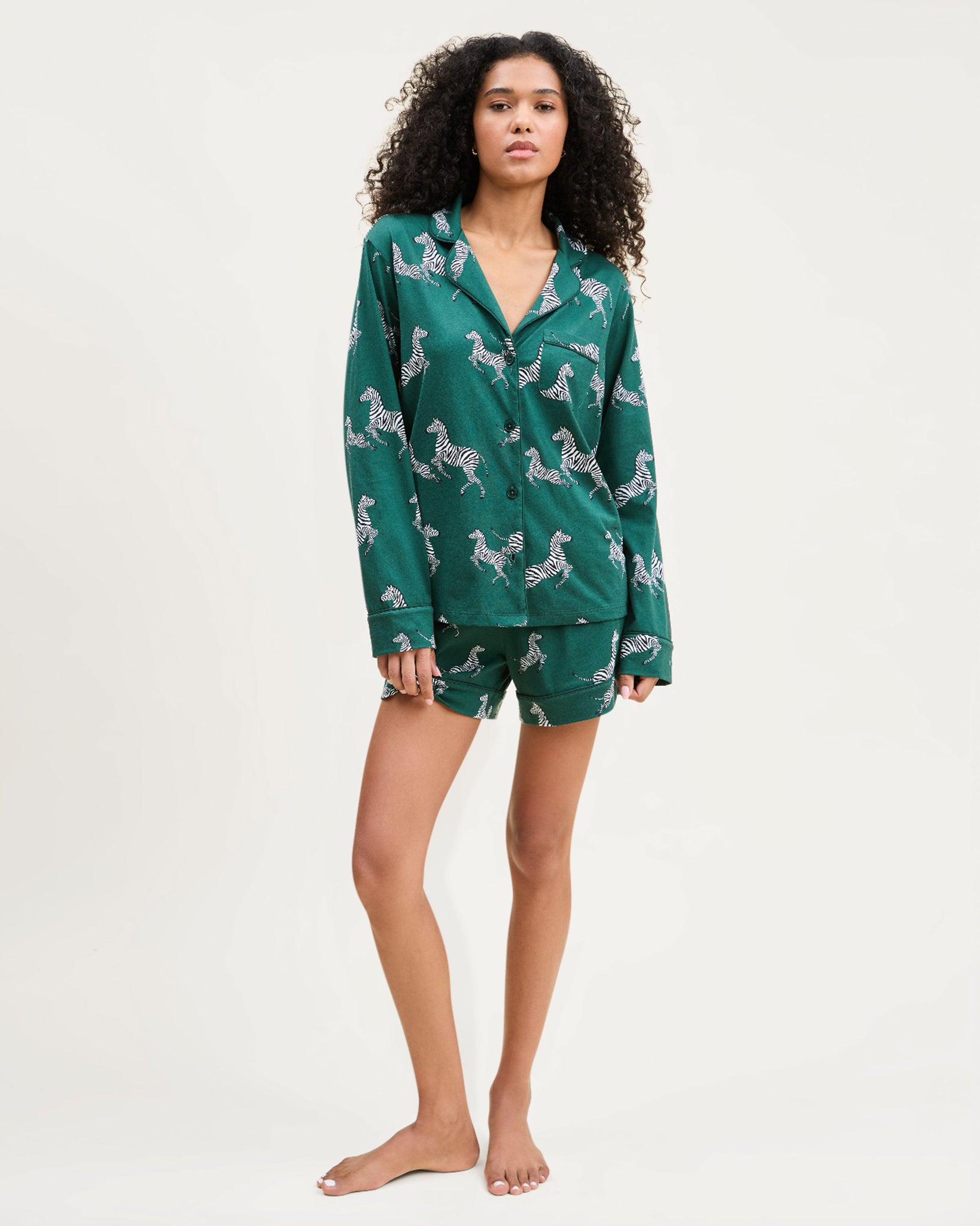 Woman wearing a green pajama set with a pattern on a white background 