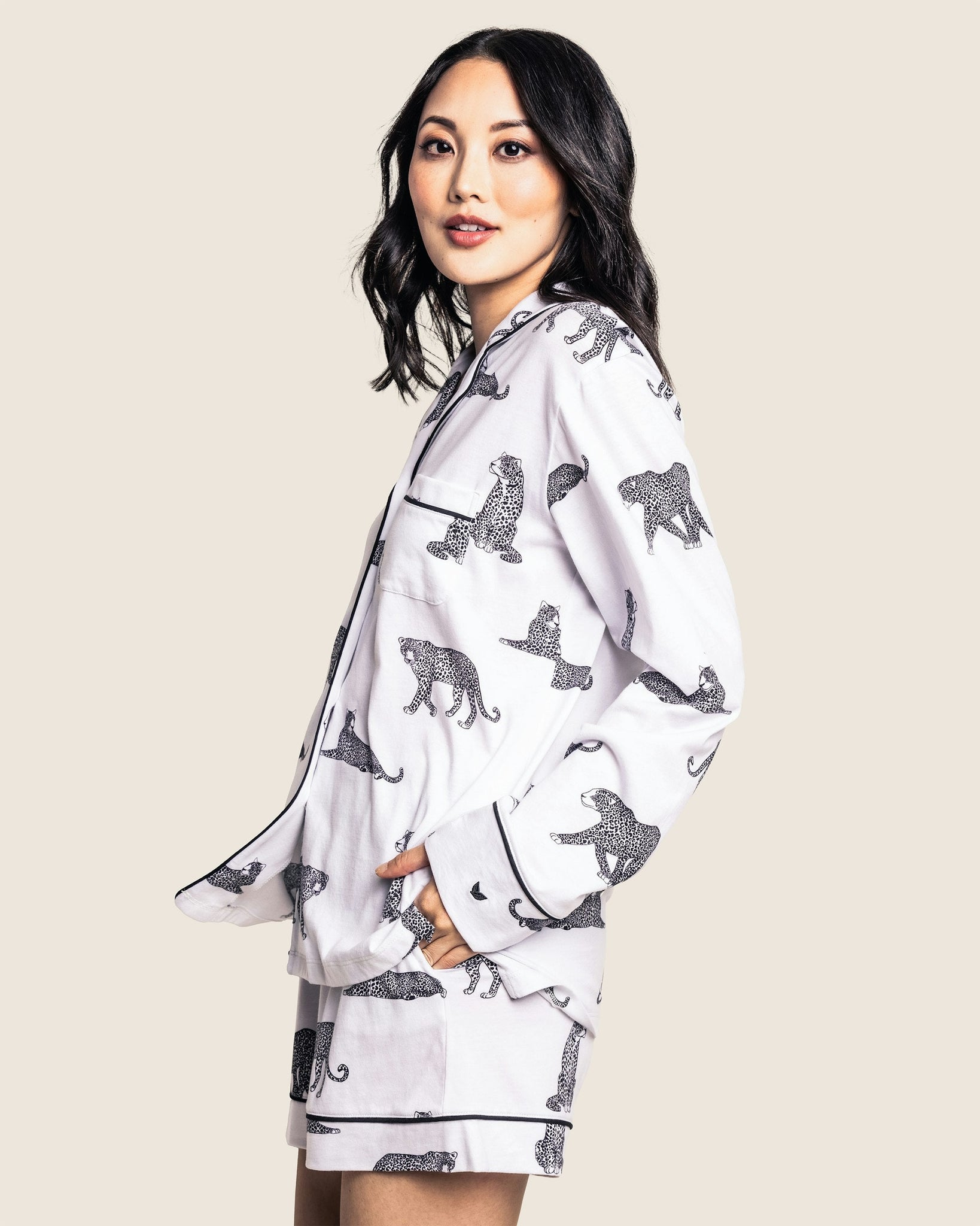 Woman wearing a white pajama set with black animal prints on a beige background