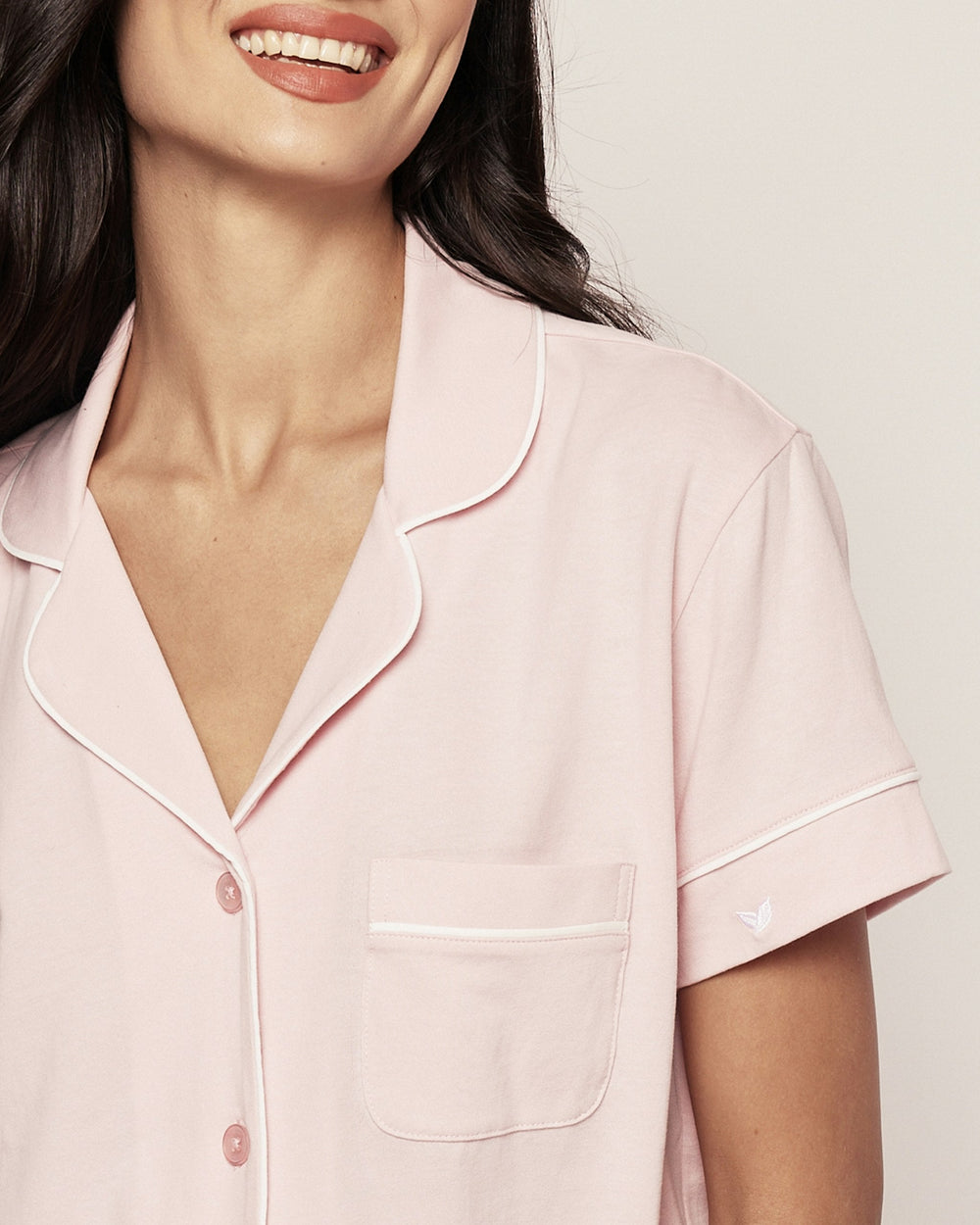 Woman wearing a light pink pajama top with a white background