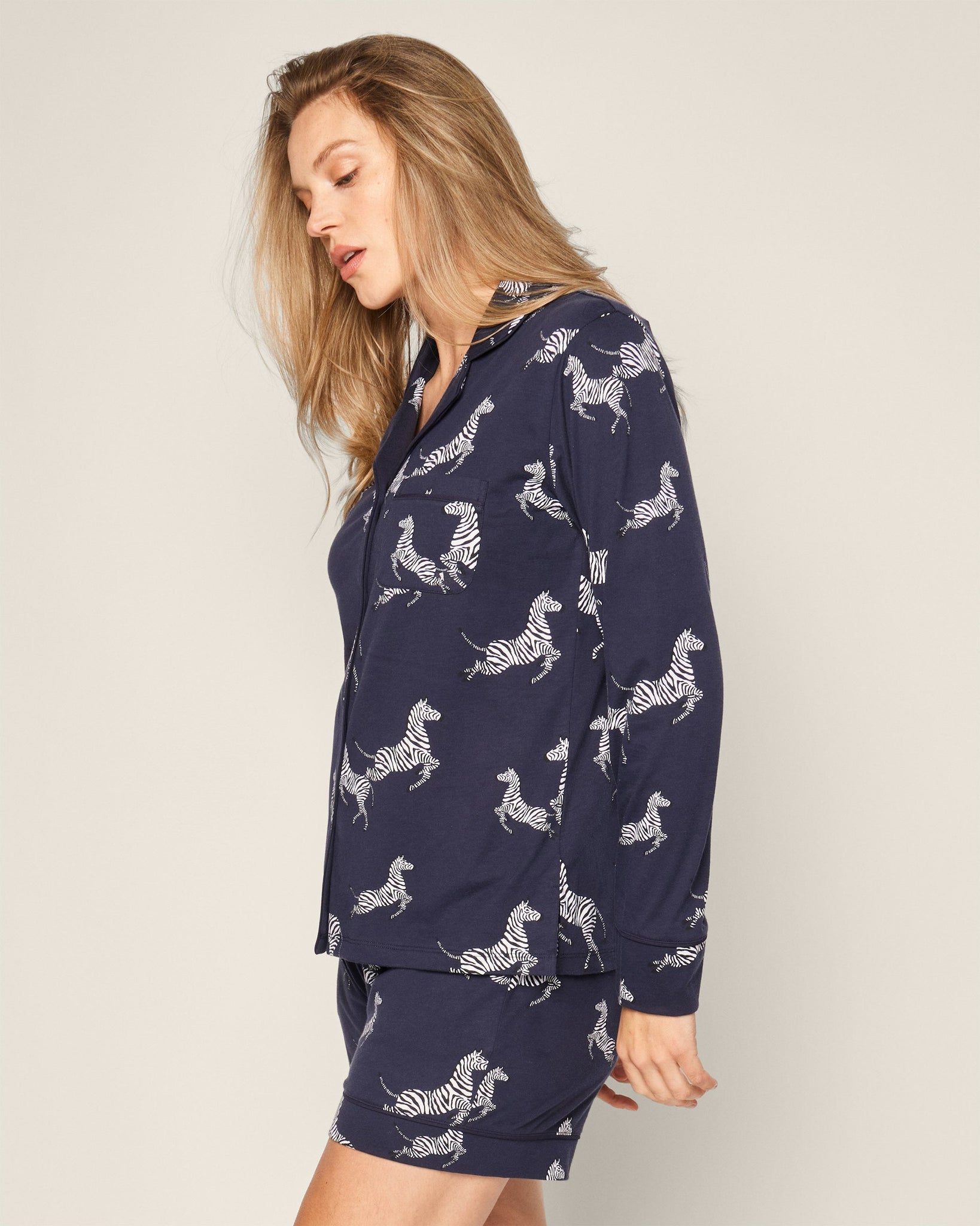 Woman wearing a navy pajama set with zebra pattern on a plain background