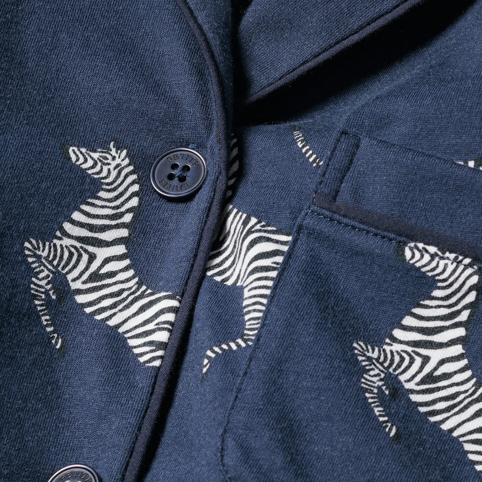 Navy blue jacket with zebra patterns and buttons on a dark background